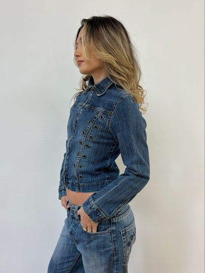 Woman wearing a blue denim jacket and jeans against a white background
