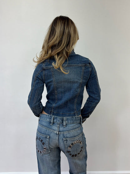 Person wearing a denim jacket and jeans against a plain background