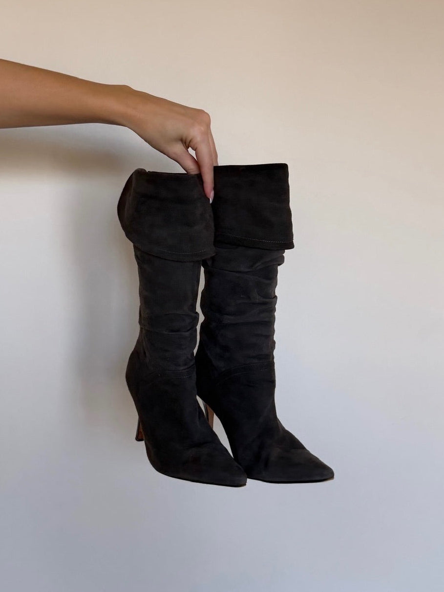 Black knee-high boots being held against a plain background