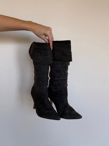Black knee-high boots being held against a plain background