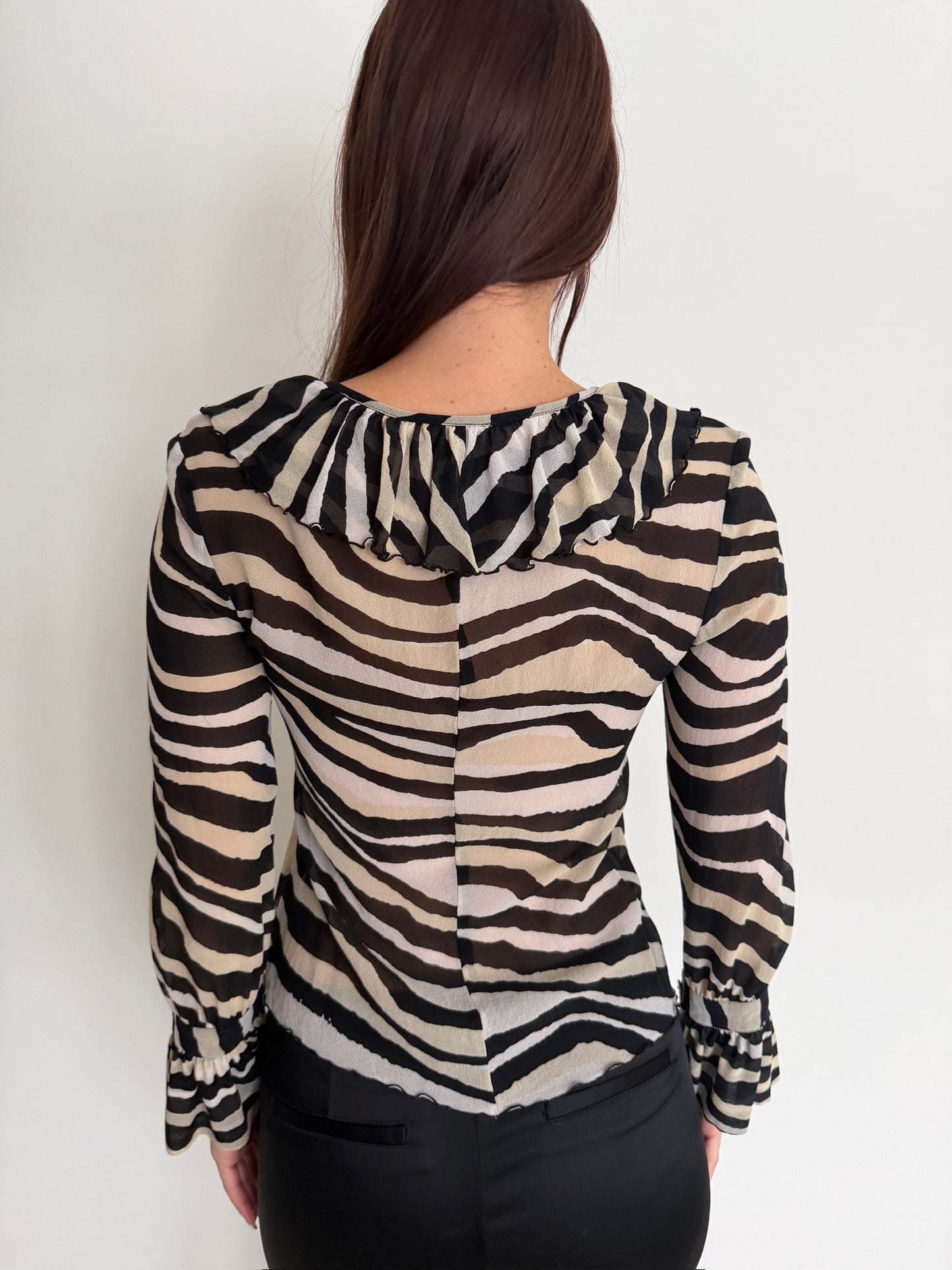 Person wearing a zebra print blouse against a white background