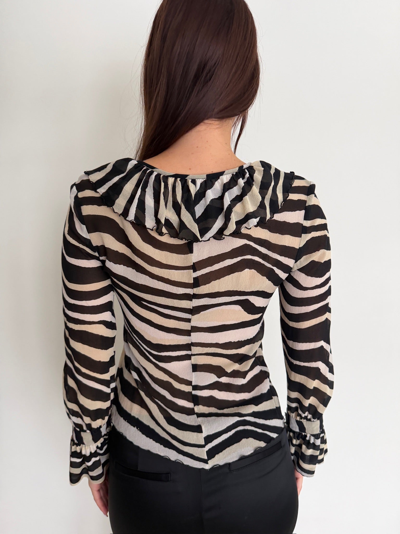 Person wearing a zebra print blouse against a white background