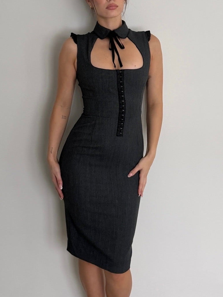 Woman wearing a black dress against a plain white wall