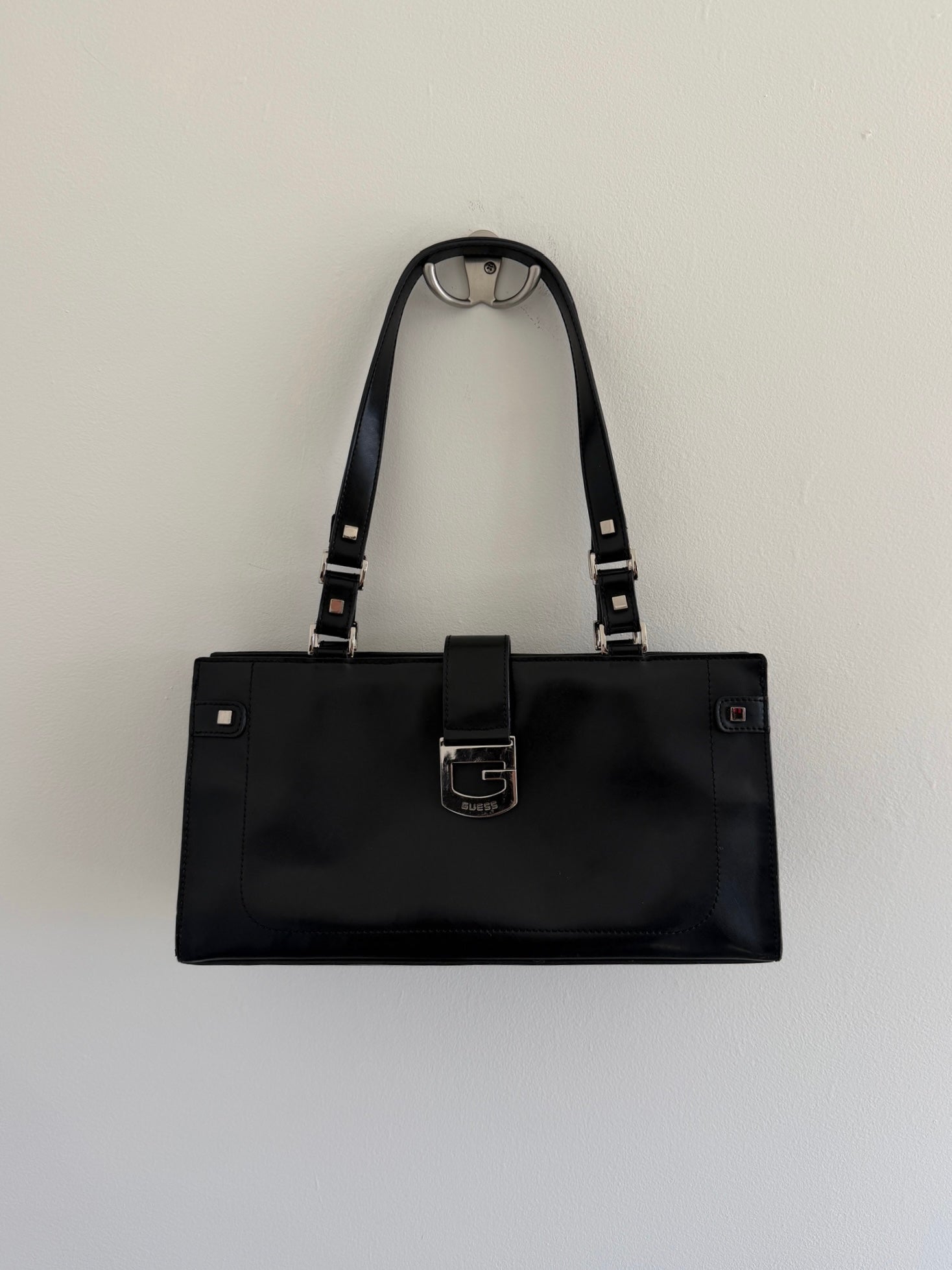 Black handbag with a strap on a light gray background