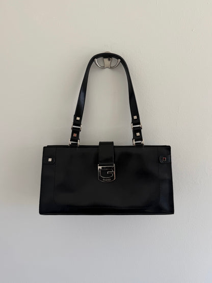 Black handbag with a strap on a light gray background