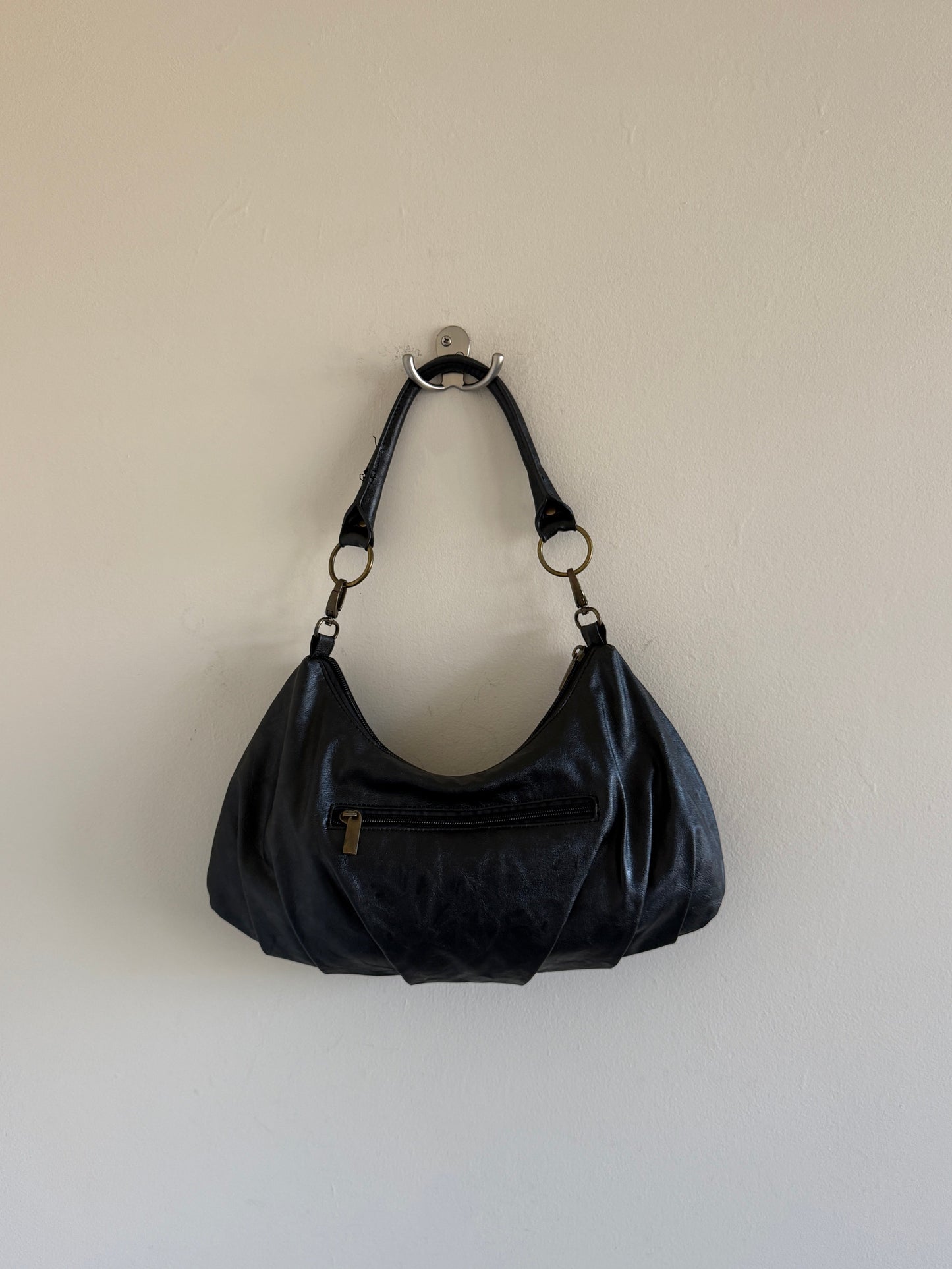 Black handbag hanging on a white wall