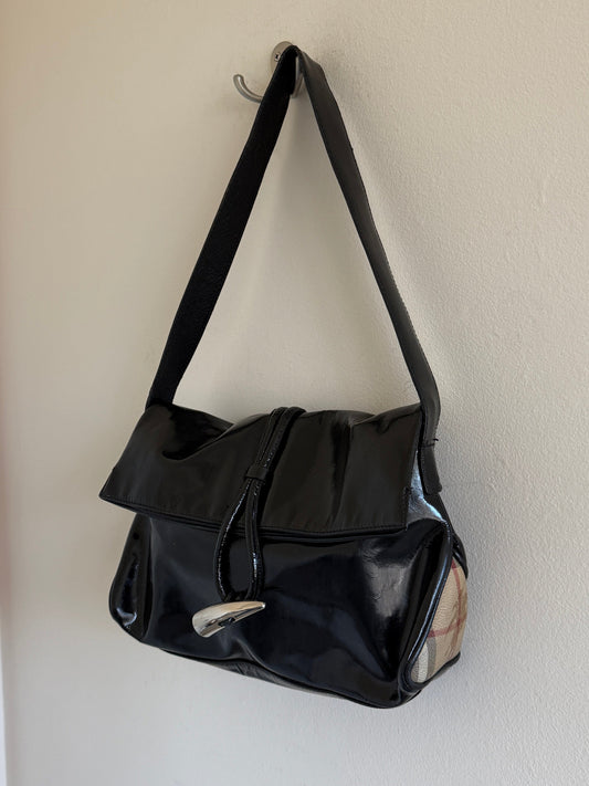 Black handbag hanging on a hook against a white wall