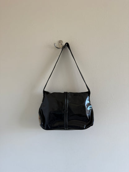 Black handbag hanging on a white wall