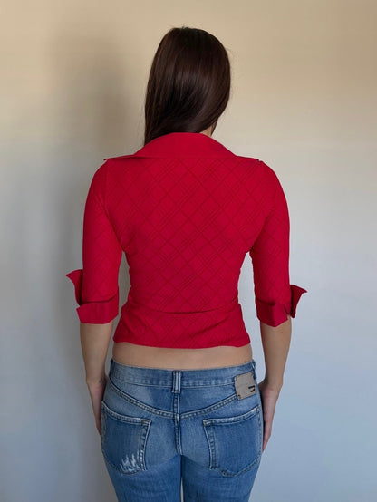 Person wearing a red quilted jacket and blue jeans against a plain background