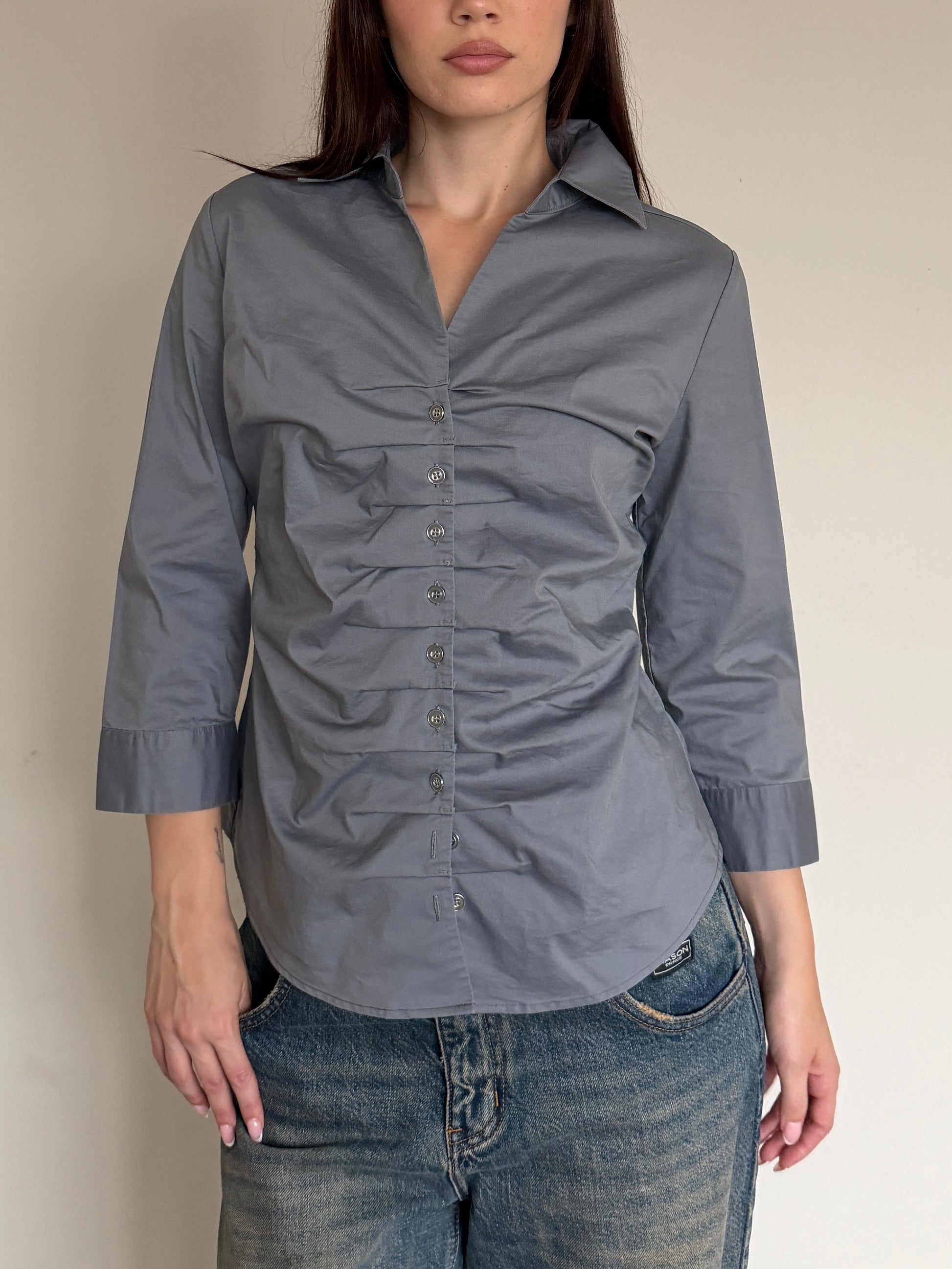 Woman wearing a gray shirt and jeans against a plain background