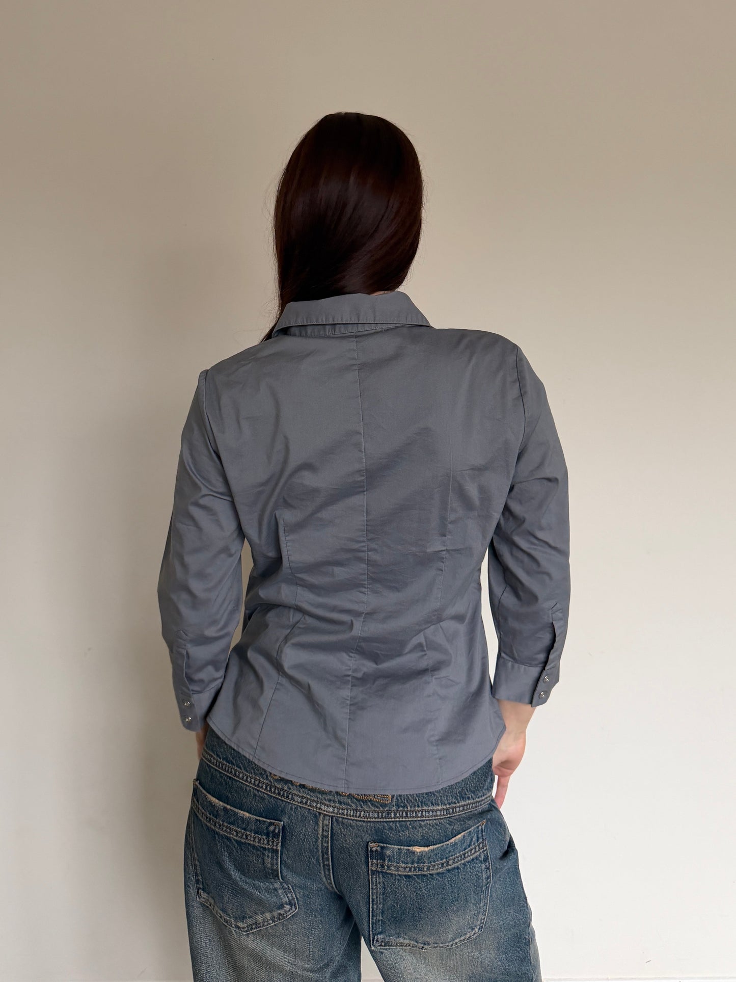 Person wearing a gray shirt and blue jeans against a plain background