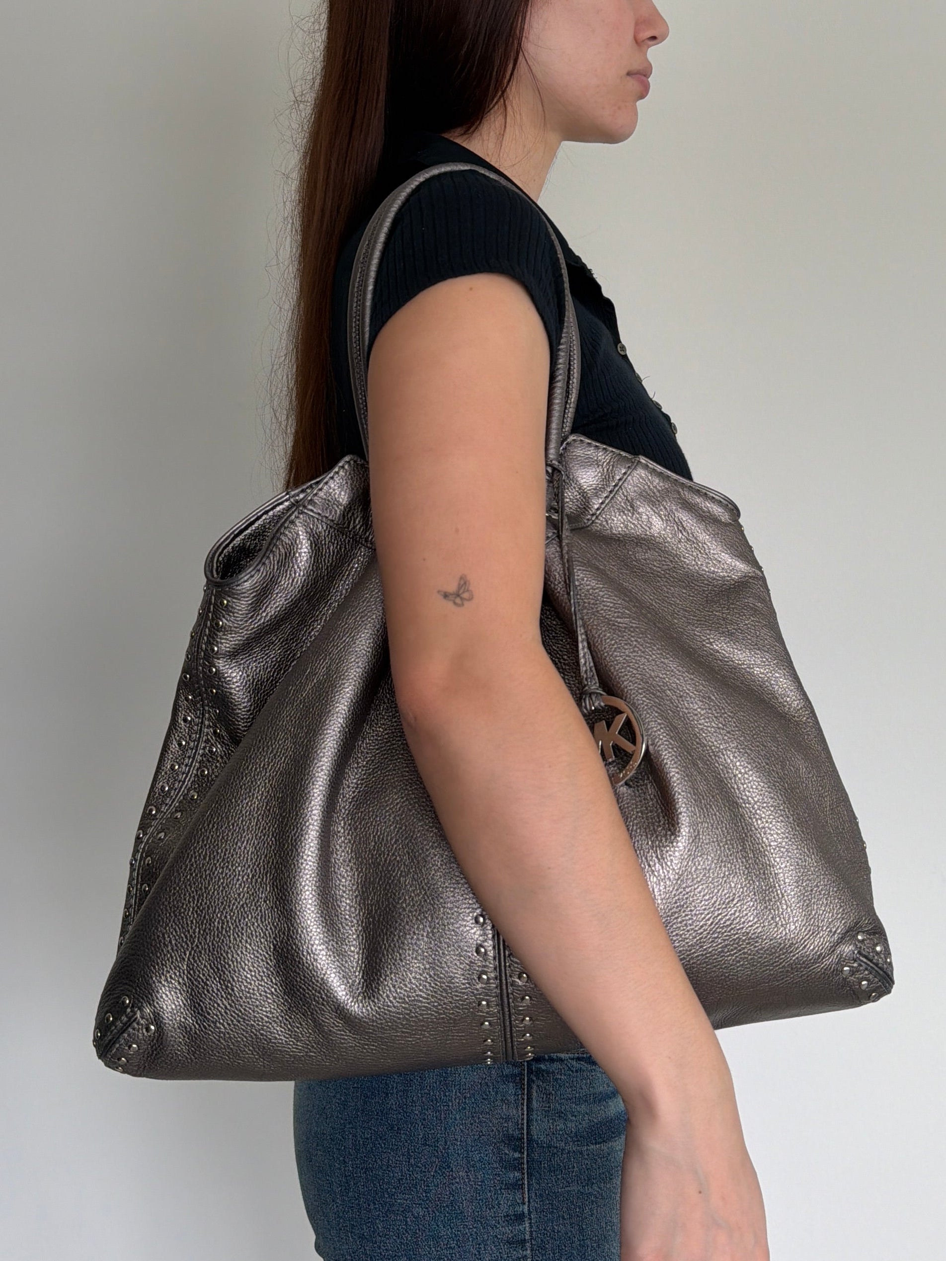 Person holding a metallic silver bag against a white background