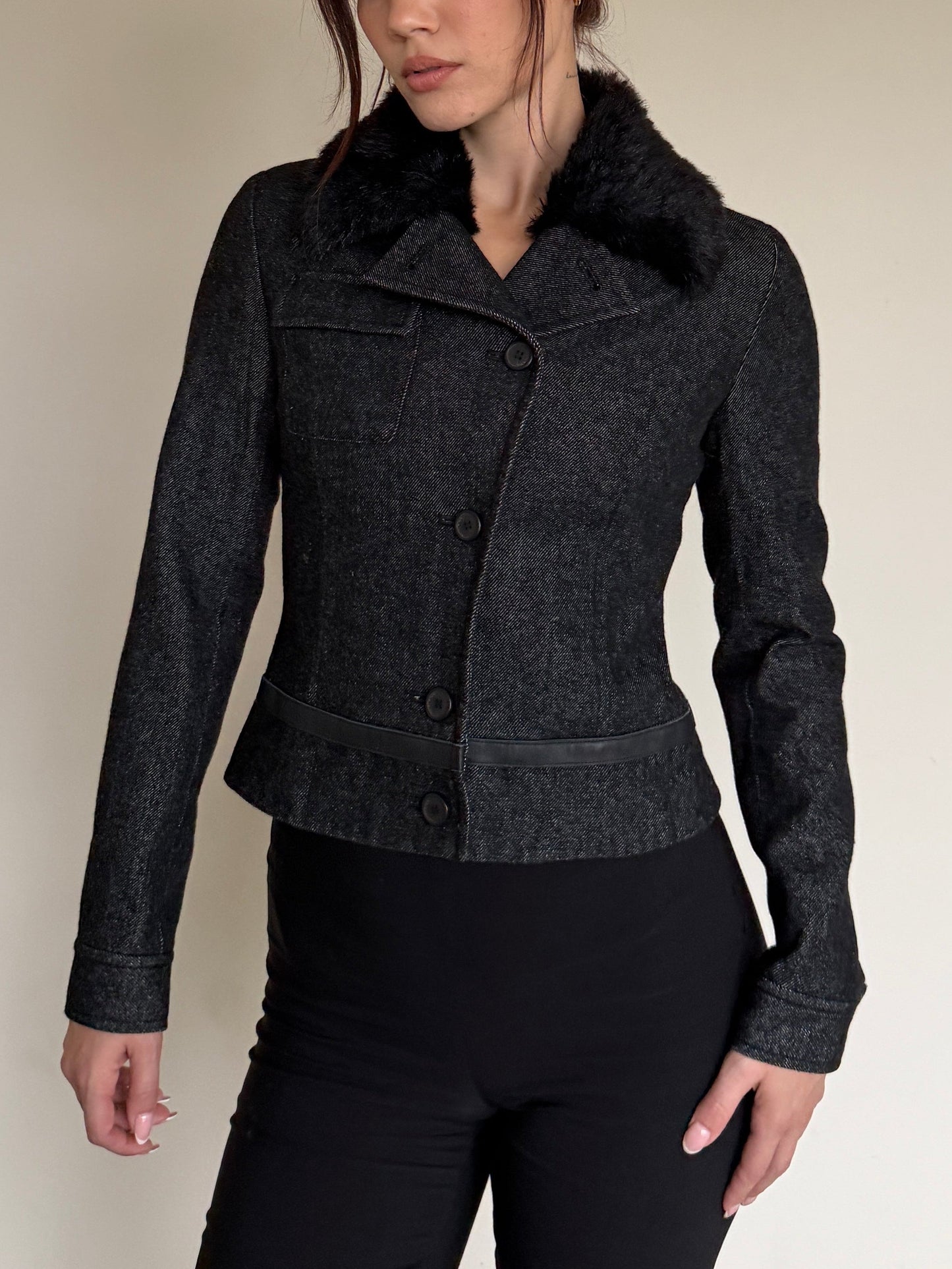 Dark gray jacket with fur collar worn by a person on a neutral background