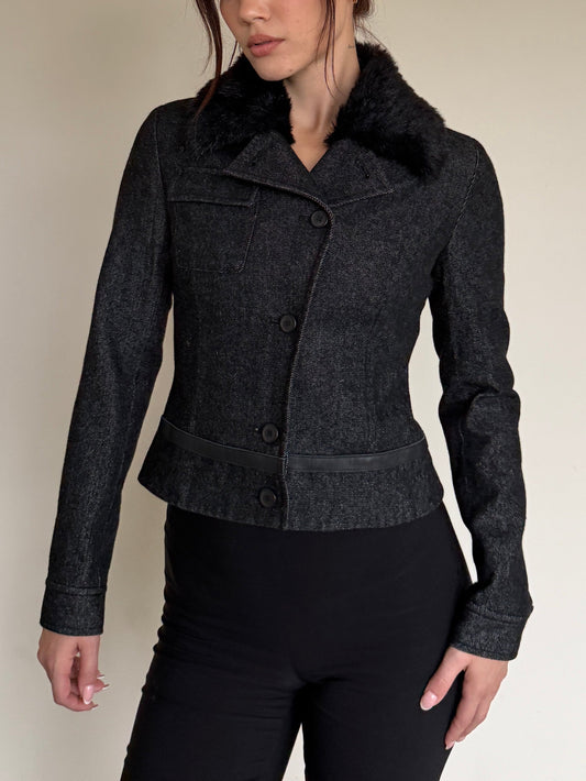 Dark gray jacket with fur collar worn by a person on a neutral background