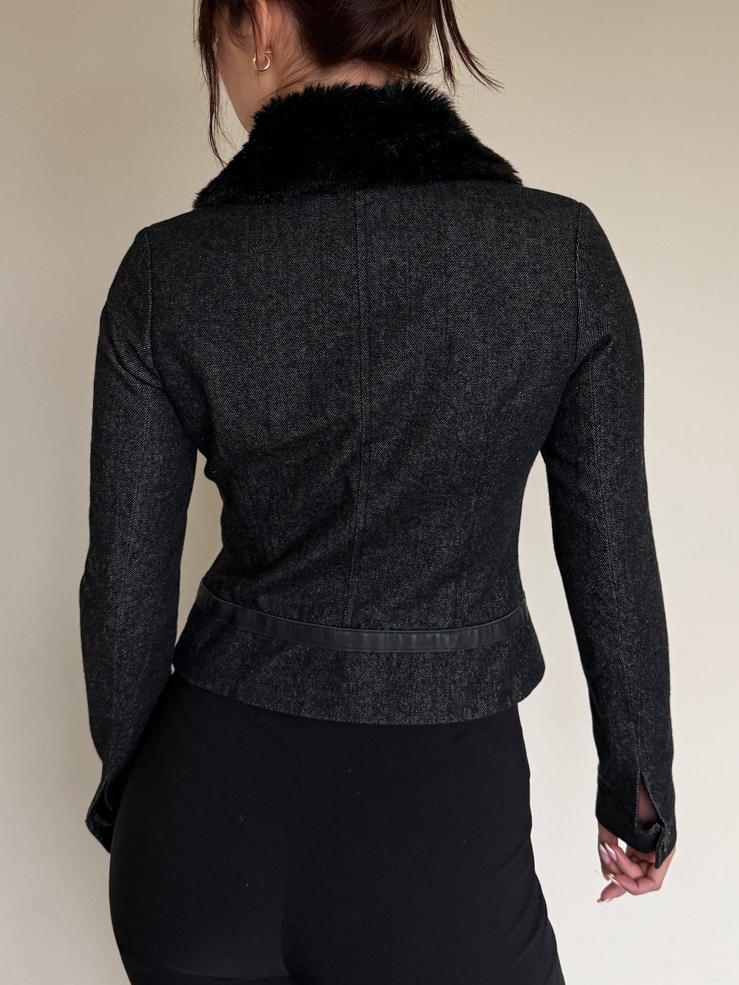 Dark gray jacket with fur collar worn by a person on a plain background