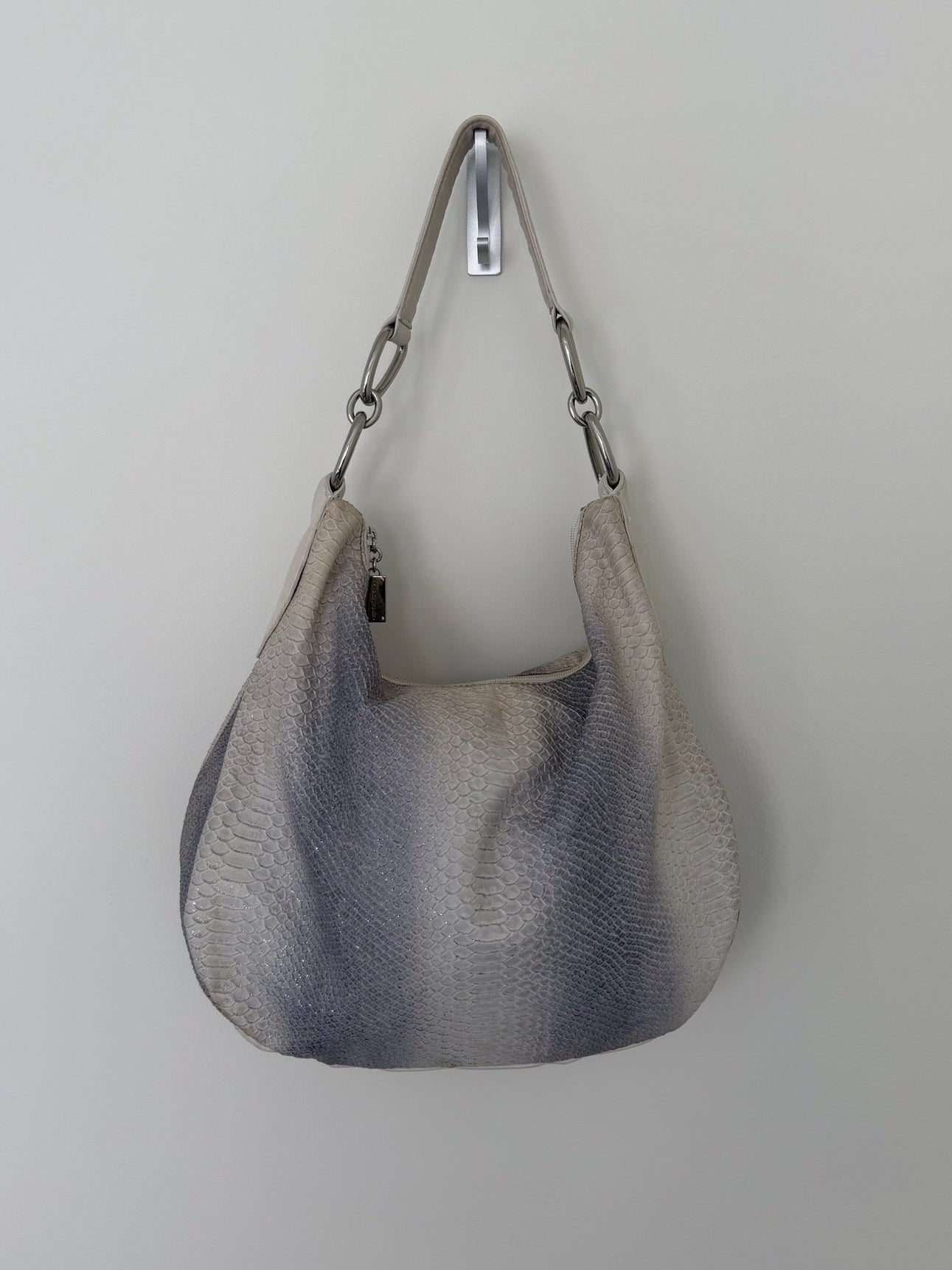 Gray textured handbag with a strap on a light gray background