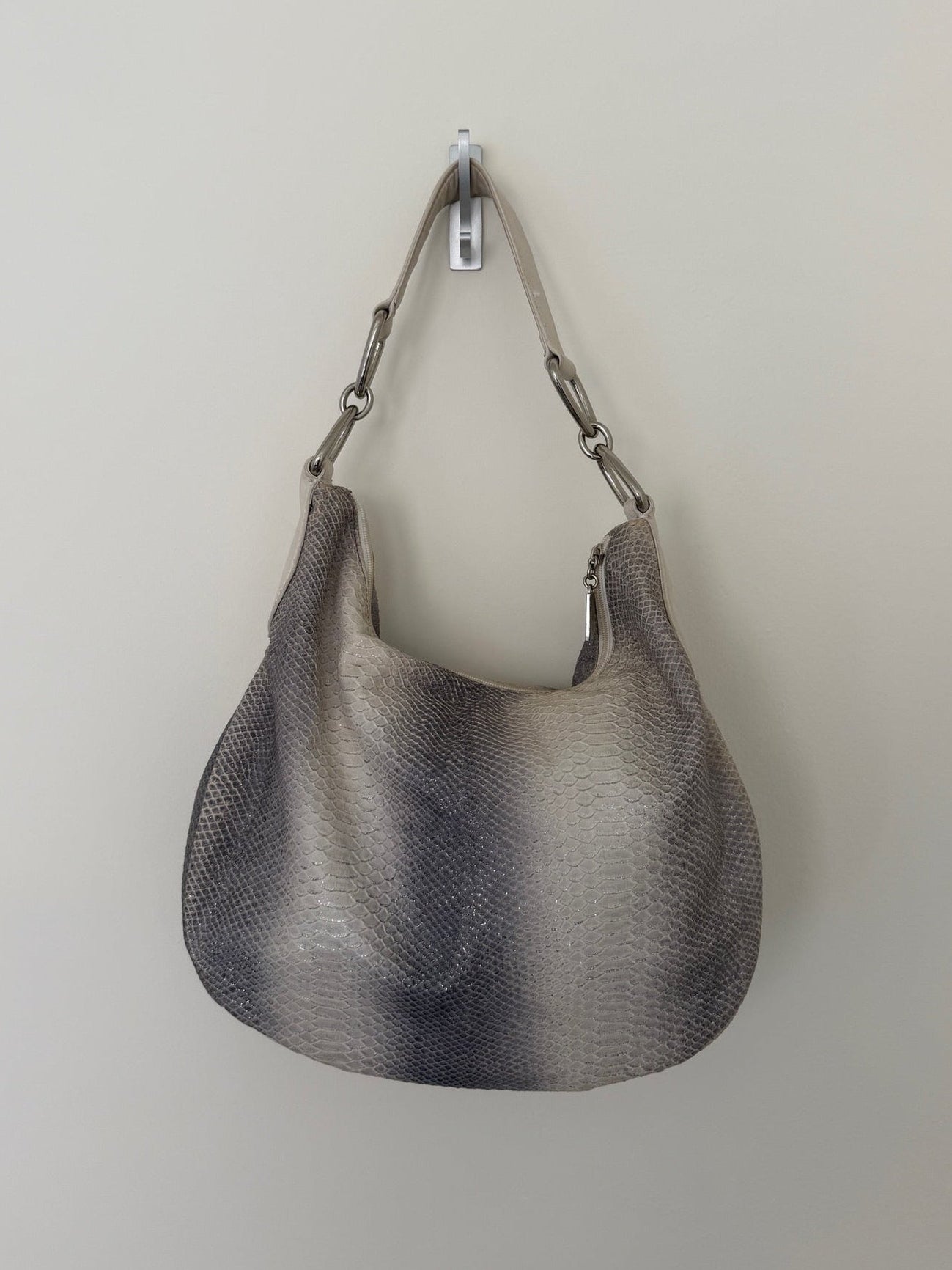 Gray textured handbag hanging on a white wall