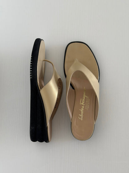 Pair of beige sandals with black soles on a light gray background