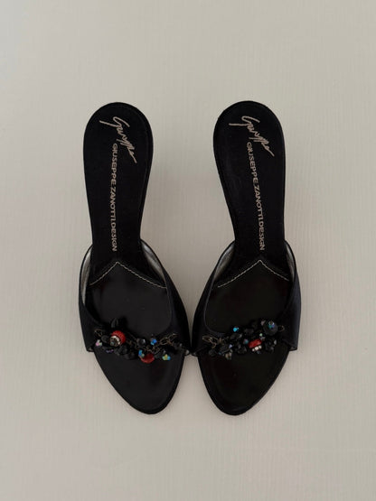 Black embellished sandals on a light gray background