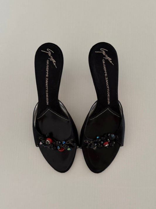 Black embellished sandals on a light gray background