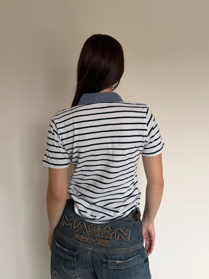 Person wearing a striped shirt and jeans with, standing against a plain background