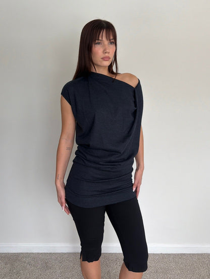 Woman wearing a black off-shoulder top and black leggings against a plain background