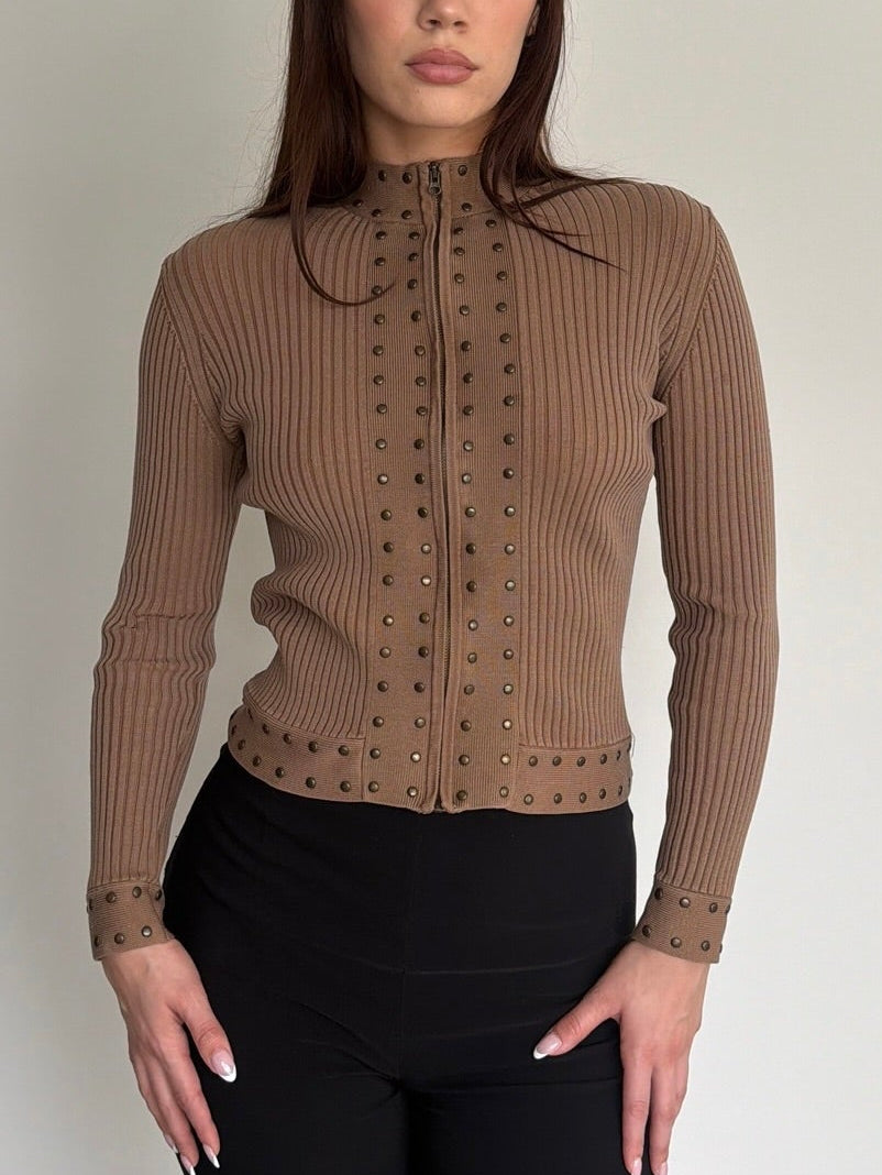 Woman wearing a brown ribbed sweater with a collar against a plain background