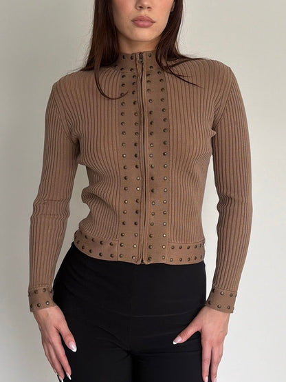 Woman wearing a brown ribbed sweater with a collar against a plain background