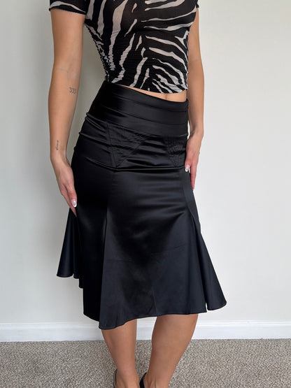 Person wearing a black skirt and zebra print top against a plain background