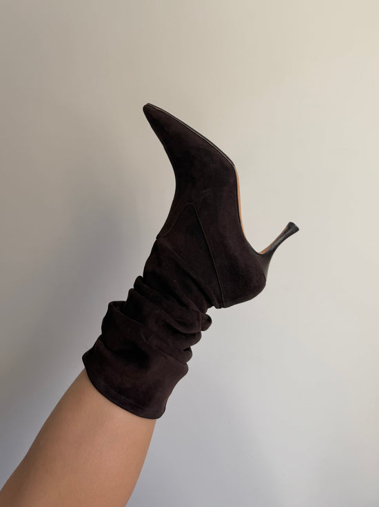Brown high-heeled boot with a sock on a neutral background