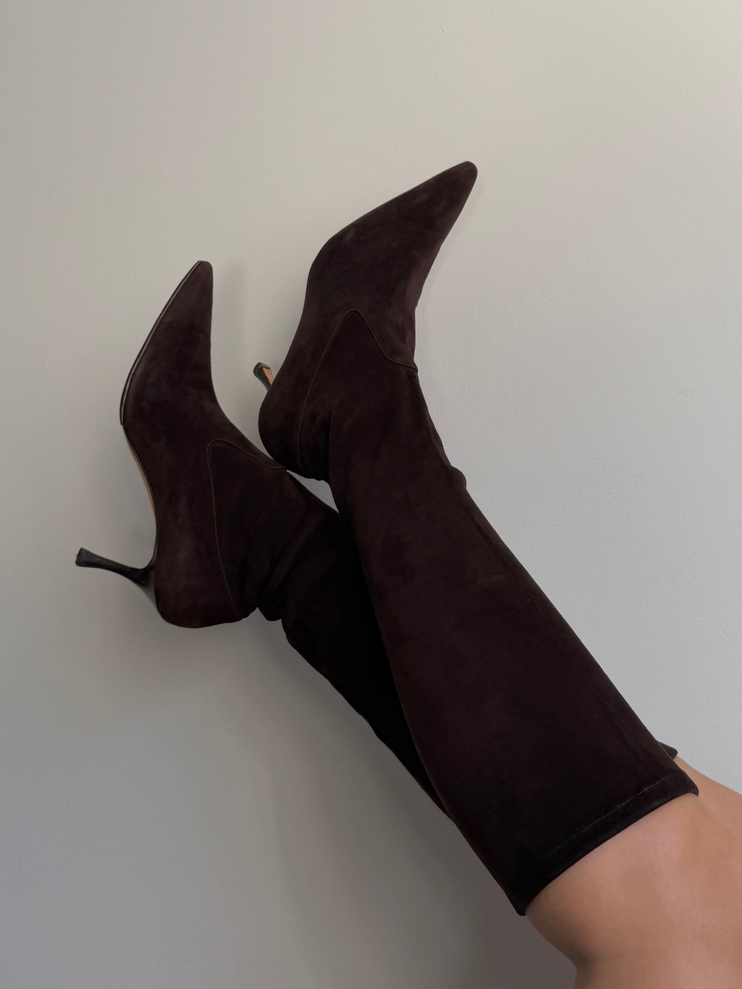 Black high-heeled boots worn with a white background