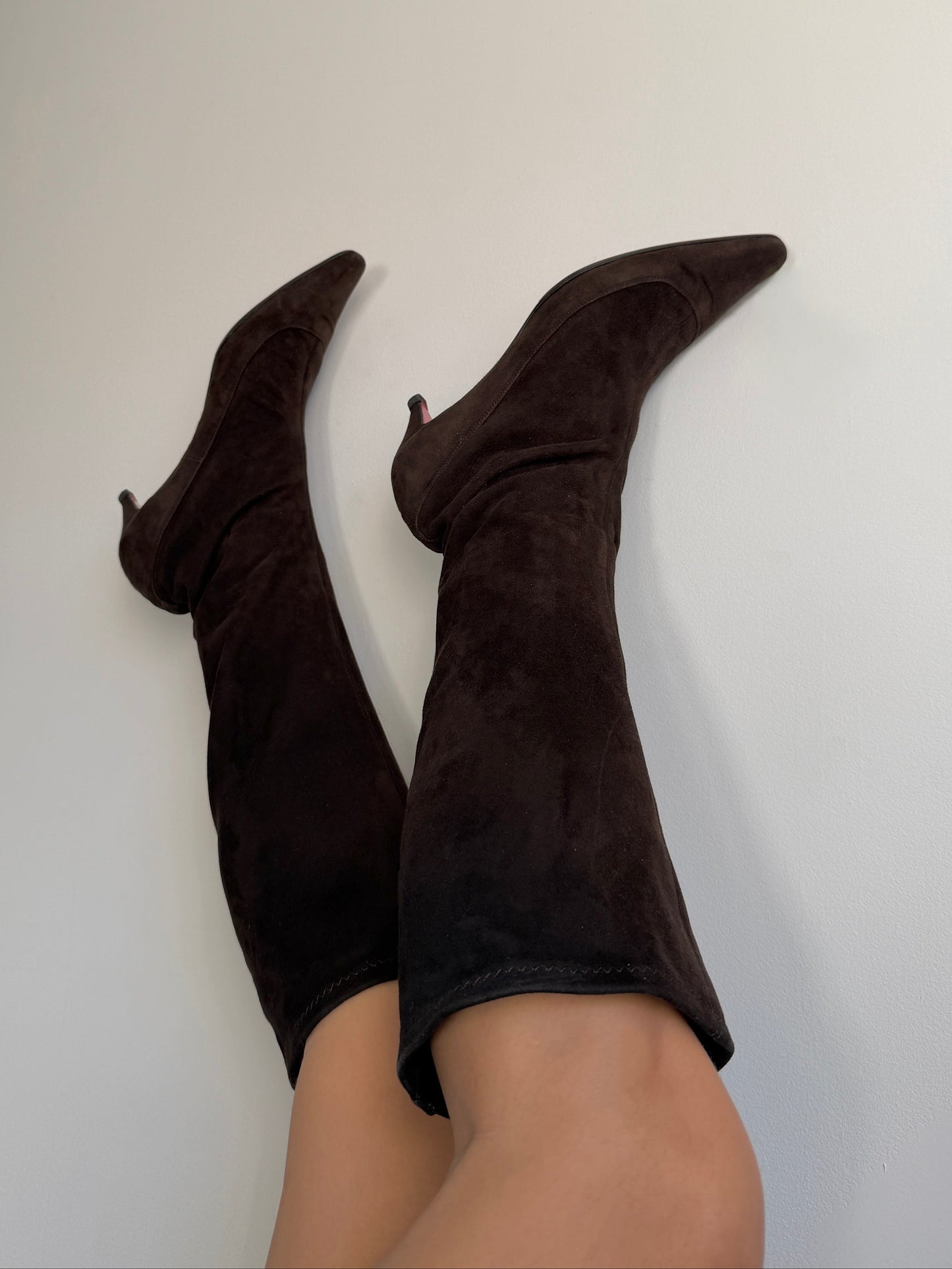 Dark brown knee-high boots on a plain background