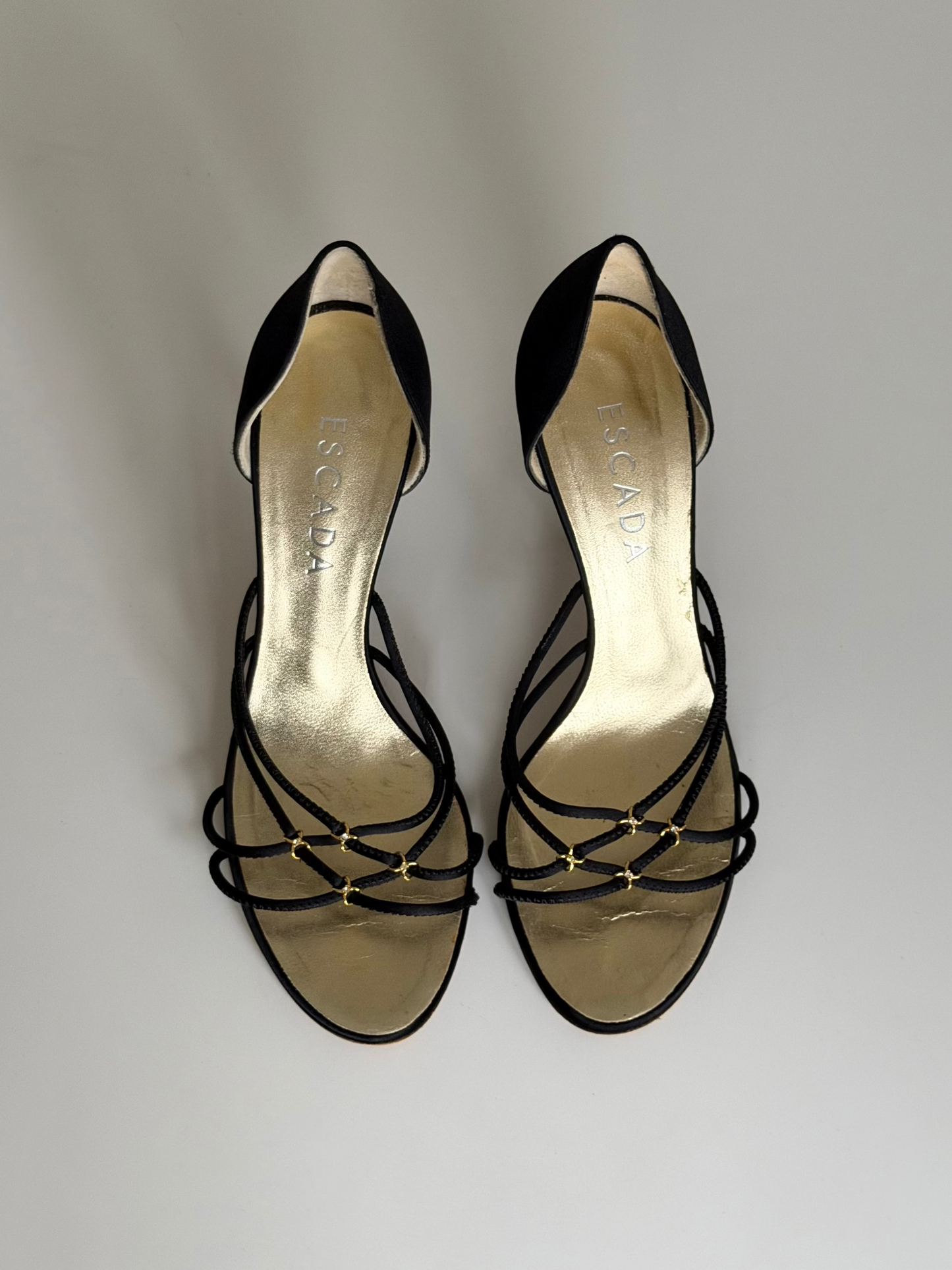 Black strappy high-heeled shoes on a light gray background