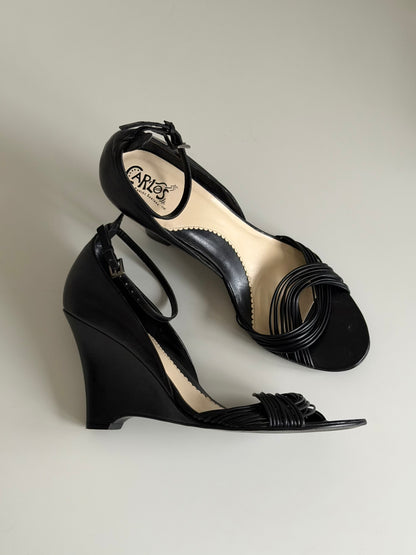 Black wedge sandals with 'Carla' branding on a light gray background