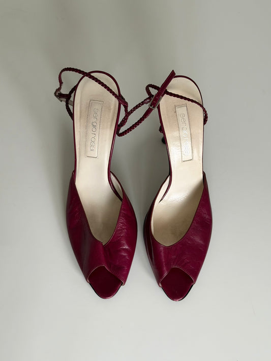 Pair of maroon open-toe shoes with ankle ties on a light gray background