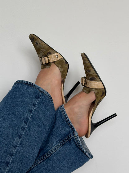 High-heeled shoes with a gold strap worn with blue jeans on a light background