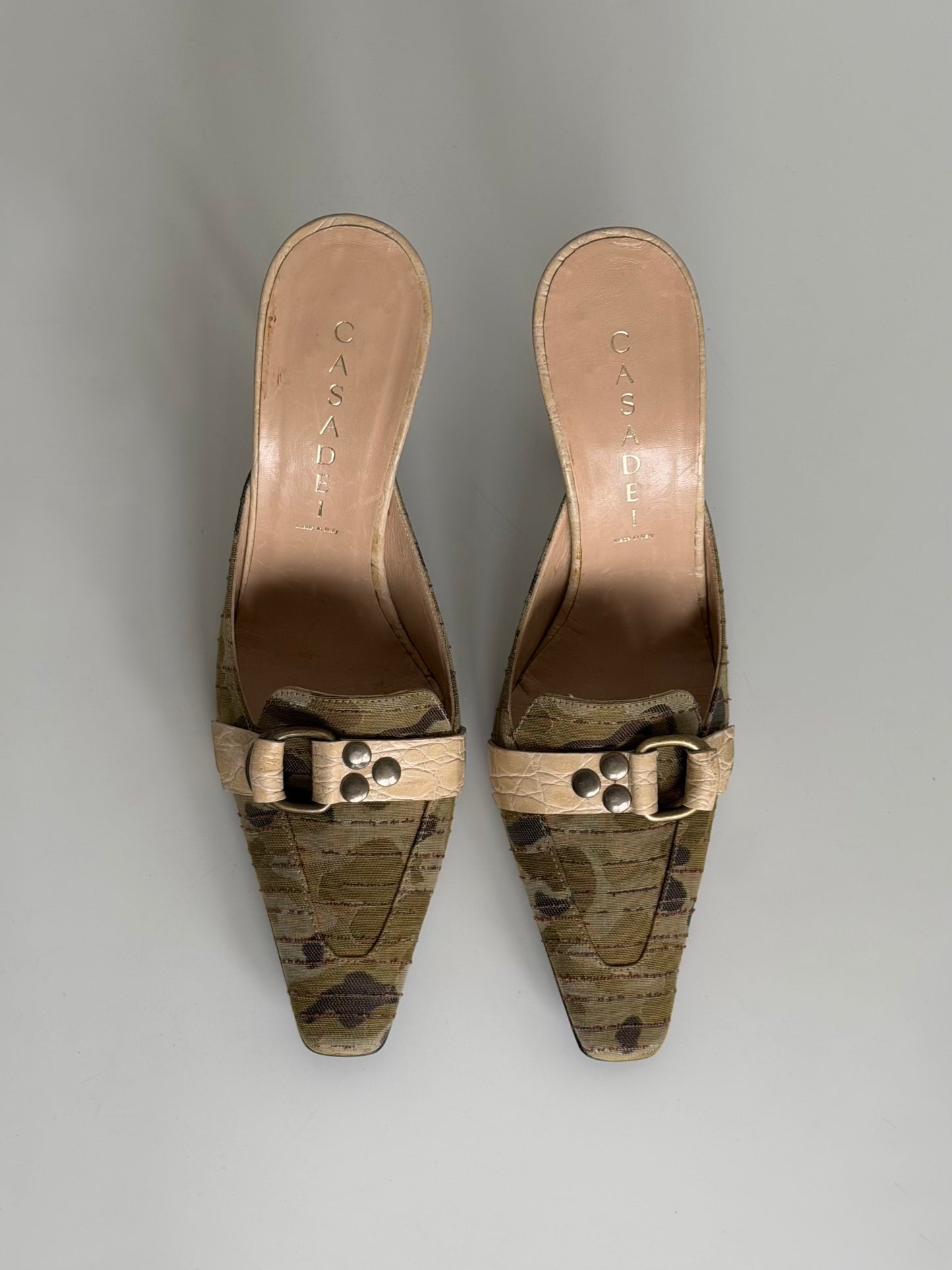 Pair of gold and brown patterned mules on a gray background