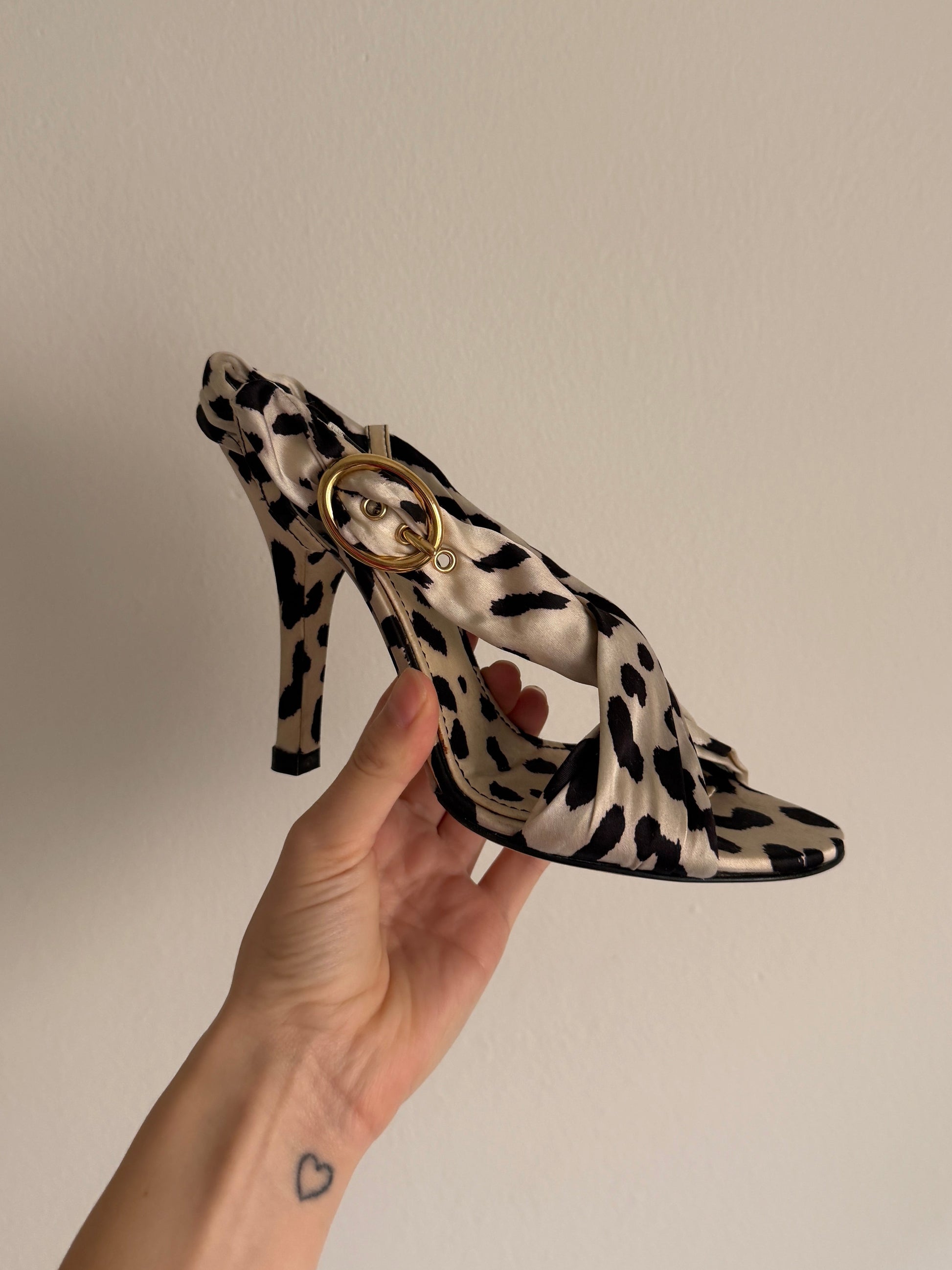 Hand holding a leopard print headband with a beige background