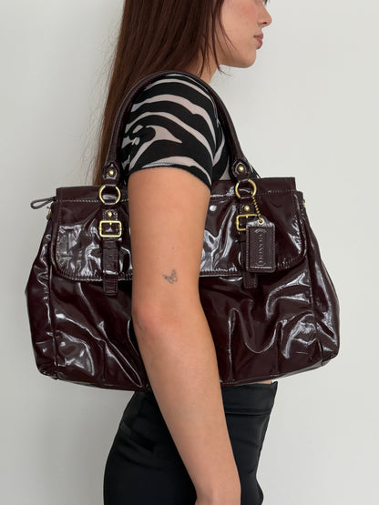 Person lying on a coach handbag with a white background