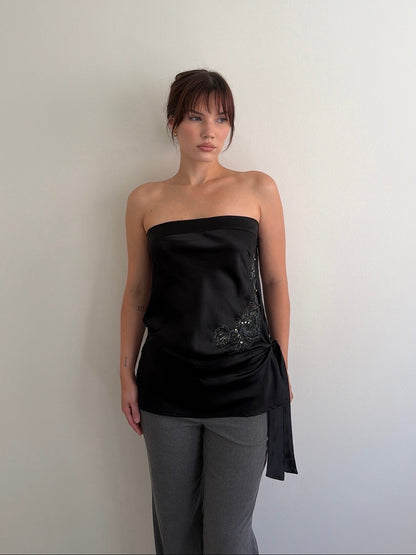 Woman wearing a black strapless top with a white background