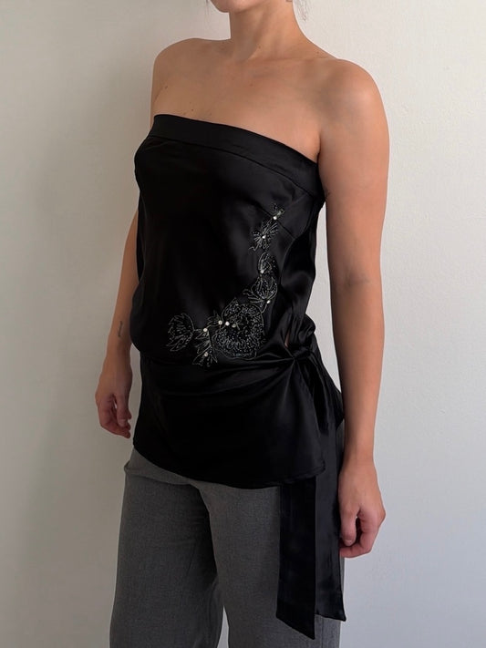 Black strapless top with embroidery worn by a person against a plain background