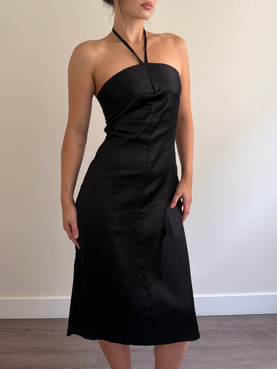 Black halter neck dress worn by a person against a plain background