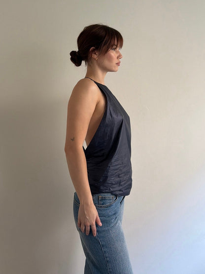 Woman wearing a dark gray tank top and blue jeans against a plain background