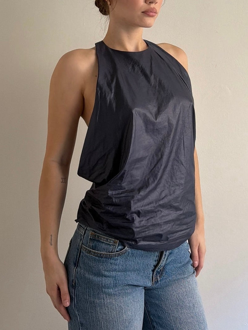 Woman wearing a dark gray sleeveless top and blue jeans against a plain background