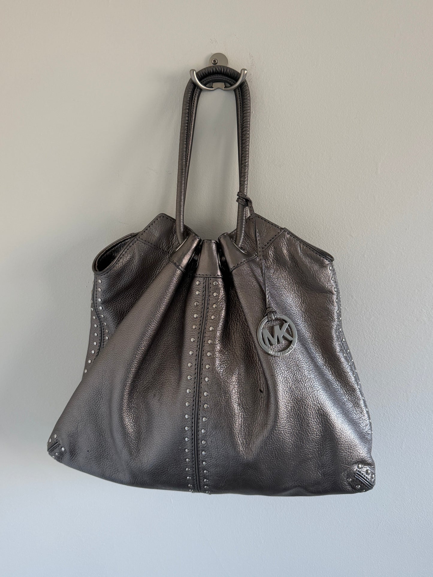 Silver metallic handbag with a brand logo on a light gray background