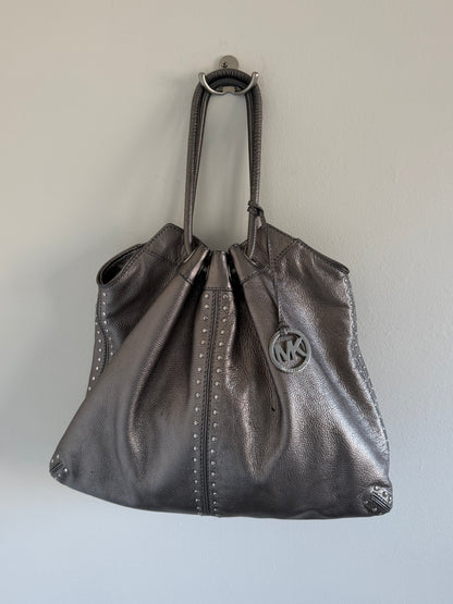 Silver metallic handbag with a brand logo on a light gray background