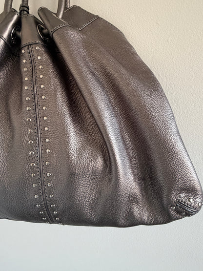 Close-up of a black leather handbag with studded details on a light gray background