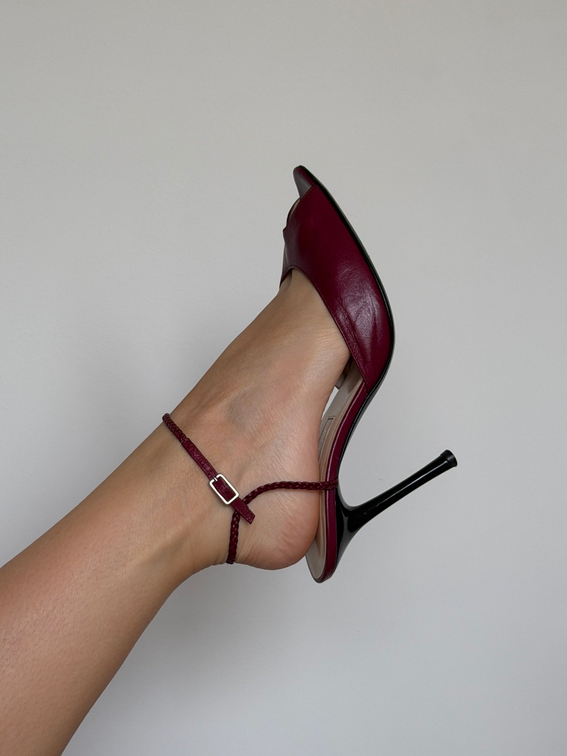 Burgundy high-heeled shoe with a thin strap on a neutral background