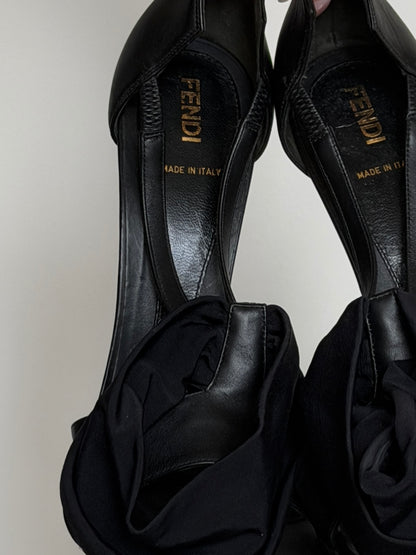 Black high-heeled shoes with 'Fendi' branding on a light gray background