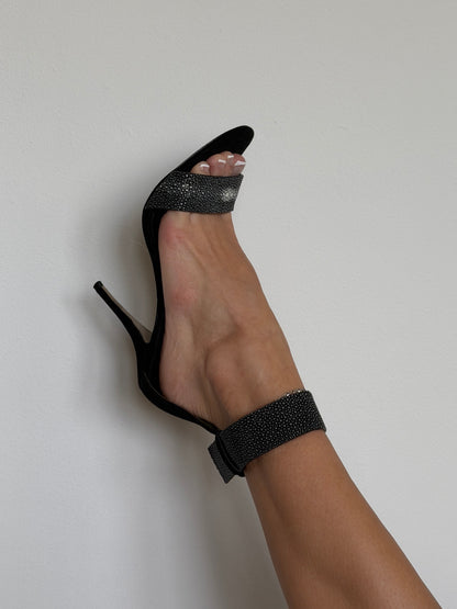 Black high-heeled shoe with glittery detail on a white background